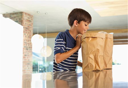 smiling boy - Boy looking through paper bag in kitchen Stock Photo - Premium Royalty-Free, Code: 6113-06908844