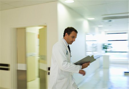 Doctor reading medical chart in hospital hallway Stock Photo - Premium Royalty-Free, Code: 6113-06909070