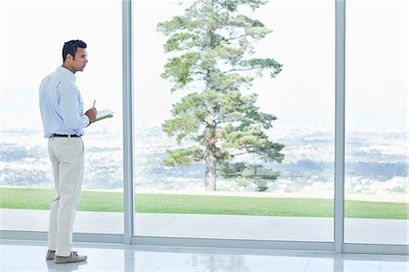 full length standing - Businessman using tablet computer at office window Stock Photo - Premium Royalty-Free, Code: 6113-06909026