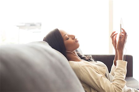 Woman listening to headphones on sofa Stock Photo - Premium Royalty-Free, Code: 6113-06909252