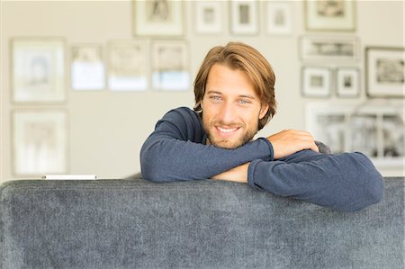 Smiling man sitting on sofa Stock Photo - Premium Royalty-Free, Code: 6113-06909258