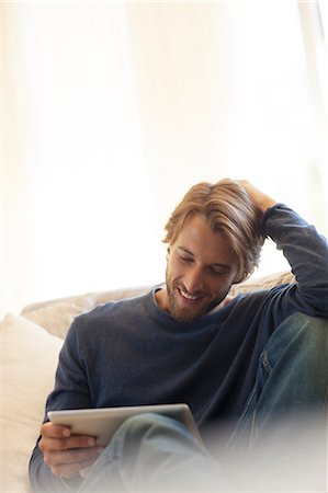 Man using tablet computer on sofa Stock Photo - Premium Royalty-Free, Code: 6113-06909222