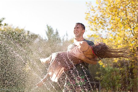 summer happy - Couple playing in sprinkler in backyard Photographie de stock - Premium Libres de Droits, Code: 6113-06909395