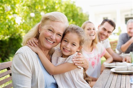 family in a table - Older woman and granddaughter smiling outdoors Stock Photo - Premium Royalty-Free, Code: 6113-06909458