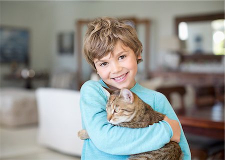 Boy hugging cat in living room Stock Photo - Premium Royalty-Free, Code: 6113-06909400