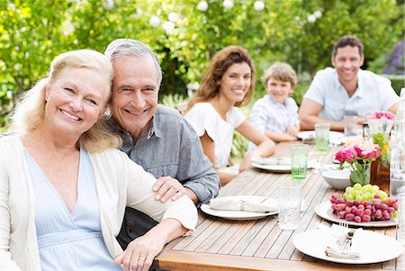 senior woman with family - Family smiling at table outdoors Stock Photo - Premium Royalty-Free, Code: 6113-06909426