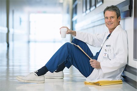 doctor white coat full body - Portrait of smiling doctor drinking coffee on floor in hospital corridor Foto de stock - Sin royalties Premium, Código: 6113-07146705