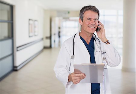 Doctor talking on cell phone in hospital corridor Stock Photo - Premium Royalty-Free, Code: 6113-07146732