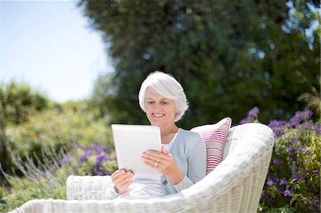 Senior woman using digital tablet in armchair Stock Photo - Premium Royalty-Free, Code: 6113-07146854