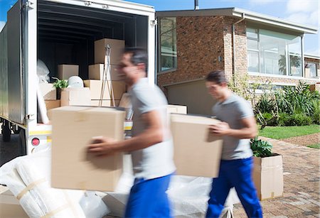 side view of man in truck - Movers carrying cardboard boxes in driveway past moving van Stock Photo - Premium Royalty-Free, Code: 6113-07147139