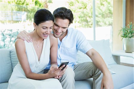simsearch:6108-05873097,k - Couple using cell phone on sofa Stock Photo - Premium Royalty-Free, Code: 6113-07147491