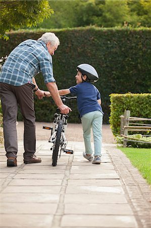 Grandfather and grandson pushing bicycle on sidewalk Stock Photo - Premium Royalty-Free, Code: 6113-07147662