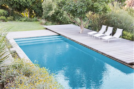 swimmingpool without people - Wooden deck and lounge chairs by swimming pool Foto de stock - Sin royalties Premium, Código: 6113-07147626