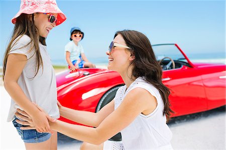 Mother and daughter smiling on beach near convertible Stock Photo - Premium Royalty-Free, Code: 6113-07147704