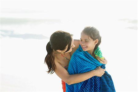 Mother wrapping daughter in towel on beach Stock Photo - Premium Royalty-Free, Code: 6113-07147738