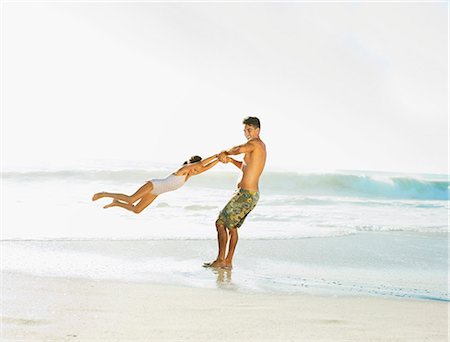 Father swinging daughter on beach Stock Photo - Premium Royalty-Free, Code: 6113-07147804