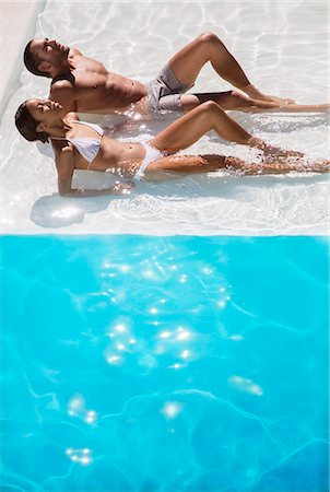 sunning - Couple sunbathing in swimming pool Photographie de stock - Premium Libres de Droits, Code: 6113-07158886