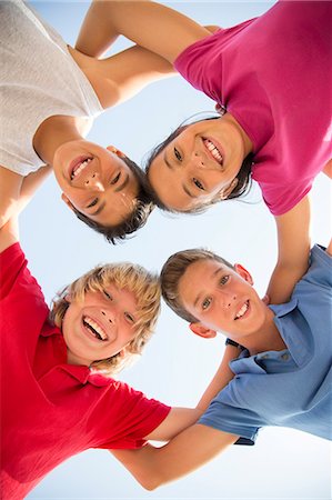 Low angle view of children smiling in huddle Stock Photo - Premium Royalty-Free, Code: 6113-07159160