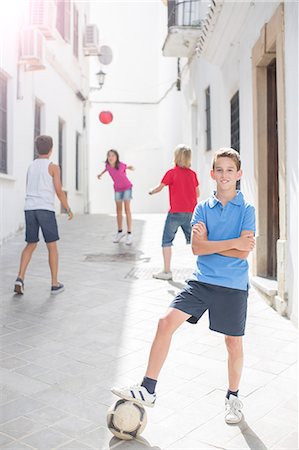 portrait of boy with arms crossed - Boy holding soccer ball in alley Stock Photo - Premium Royalty-Free, Code: 6113-07159177