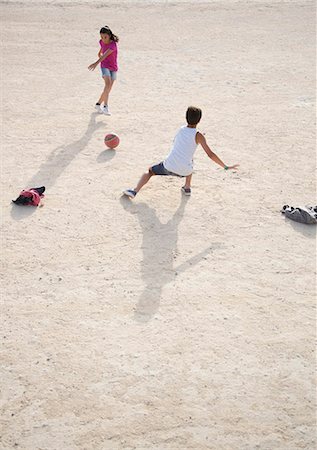 Children playing with soccer ball in sand Stock Photo - Premium Royalty-Free, Code: 6113-07159176