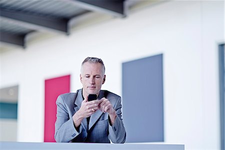 simsearch:6113-07543477,k - Businessman using cell phone in lobby Stock Photo - Premium Royalty-Free, Code: 6113-07159105