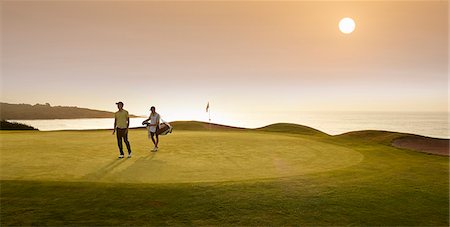 Golfer and caddy walking on golf course Photographie de stock - Premium Libres de Droits, Code: 6113-07159272