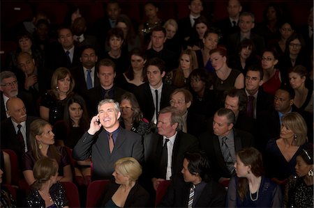 Man talking on cell phone in theater audience Stock Photo - Premium Royalty-Free, Code: 6113-07159343