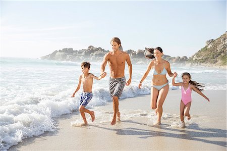 pre teen girl smiling on beach - Family running together in waves Stock Photo - Premium Royalty-Free, Code: 6113-07159564