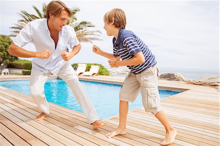 play fighting - Father and son playing by pool Stock Photo - Premium Royalty-Free, Code: 6113-07159601