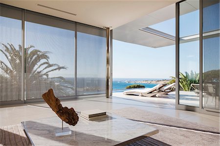 Modern living room and patio overlooking ocean Photographie de stock - Premium Libres de Droits, Code: 6113-07159844