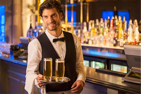 Portrait of well dressed bartender carrying beers on tray Stock Photo - Premium Royalty-Free, Code: 6113-07159883