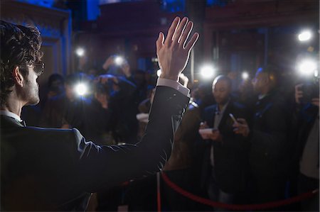 paparazzi - Rear view of male celebrity waving to paparazzi at red carpet event Stock Photo - Premium Royalty-Free, Code: 6113-07160076