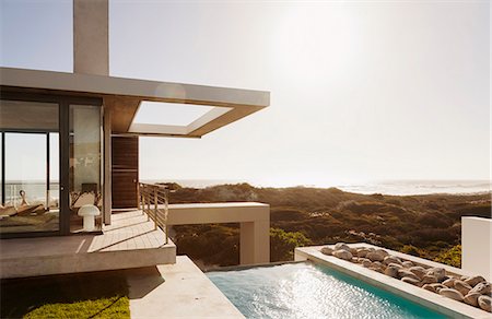 pool outside modern house - Modern house and swimming pool overlooking ocean Stock Photo - Premium Royalty-Free, Code: 6113-07160157