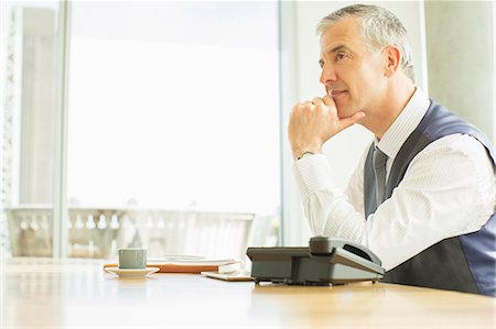 sitting at the side of the window - Businessman sitting at desk in office Stock Photo - Premium Royalty-Free, Code: 6113-07160423