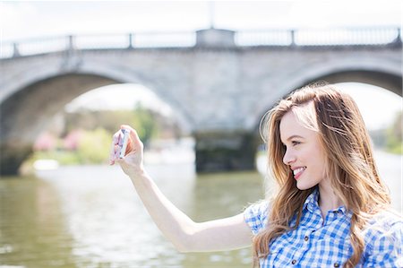 Woman taking self-portrait along river Stock Photo - Premium Royalty-Free, Code: 6113-07160585