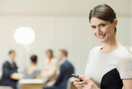Businesswoman using cell phone in office Stock Photo - Premium Royalty-Free, Code: 6113-07160529