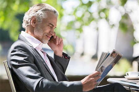 relaxing 40s - Businessman reading magazine at sidewalk cafe Stock Photo - Premium Royalty-Free, Code: 6113-07160650