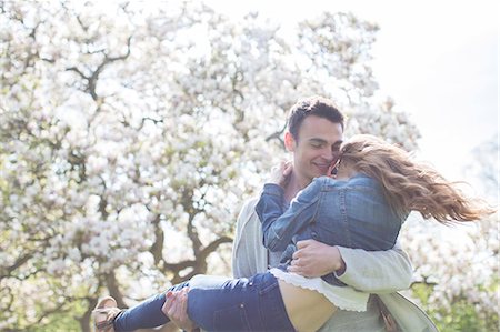 romantic lift hug - Man lifting woman under tree with white blossoms Stock Photo - Premium Royalty-Free, Code: 6113-07160633