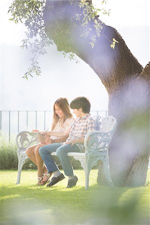 simsearch:6113-06908842,k - Brother and sister using digital tablet on bench under tree Stock Photo - Premium Royalty-Free, Code: 6113-07242071