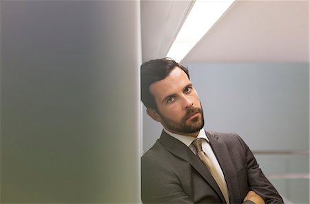 Serious businessman leaning against office wall Stock Photo - Premium Royalty-Free, Code: 6113-07242136