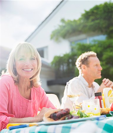 Smiling woman at table in backyard Stock Photo - Premium Royalty-Free, Code: 6113-07242444