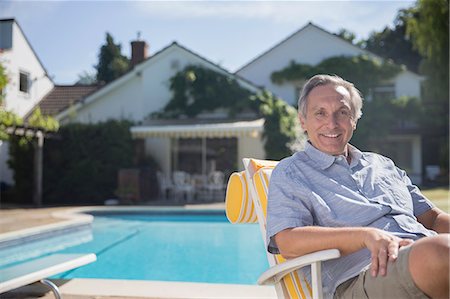 Smiling man in lounge chair at poolside Stock Photo - Premium Royalty-Free, Code: 6113-07242475
