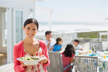 family on patio - Woman holding salad bowl on sunny patio overlooking ocean Stock Photo - Premium Royalty-Free, Code: 6113-07242546