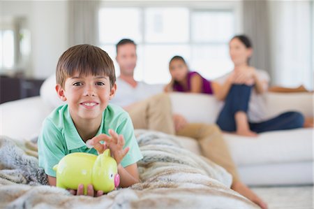 Boy with piggy bank on sofa in living room Stock Photo - Premium Royalty-Free, Code: 6113-07242639