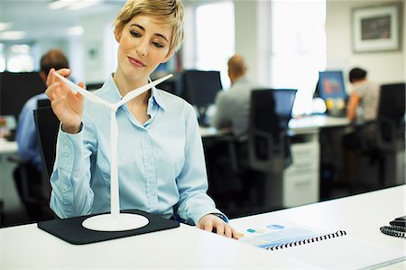 energy concept - Businesswoman examining toy wind turbine in office Stock Photo - Premium Royalty-Free, Code: 6113-07242752