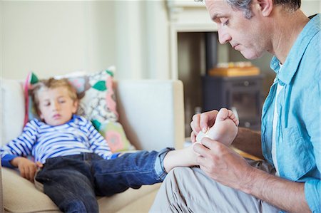 Father bandaging son's foot Stock Photo - Premium Royalty-Free, Code: 6113-07242946