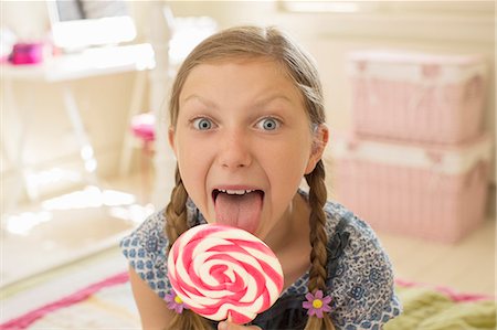 Girl licking lollipop in bedroom Stock Photo - Premium Royalty-Free, Code: 6113-07243033