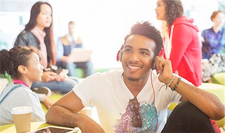 University student listening to headphones in lounge Stock Photo - Premium Royalty-Free, Code: 6113-07243366