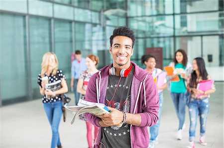 Smiling university student carrying books Stock Photo - Premium Royalty-Free, Code: 6113-07243382