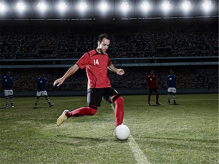 stadium at night - Soccer player kicking ball on field Stock Photo - Premium Royalty-Free, Code: 6113-07310563